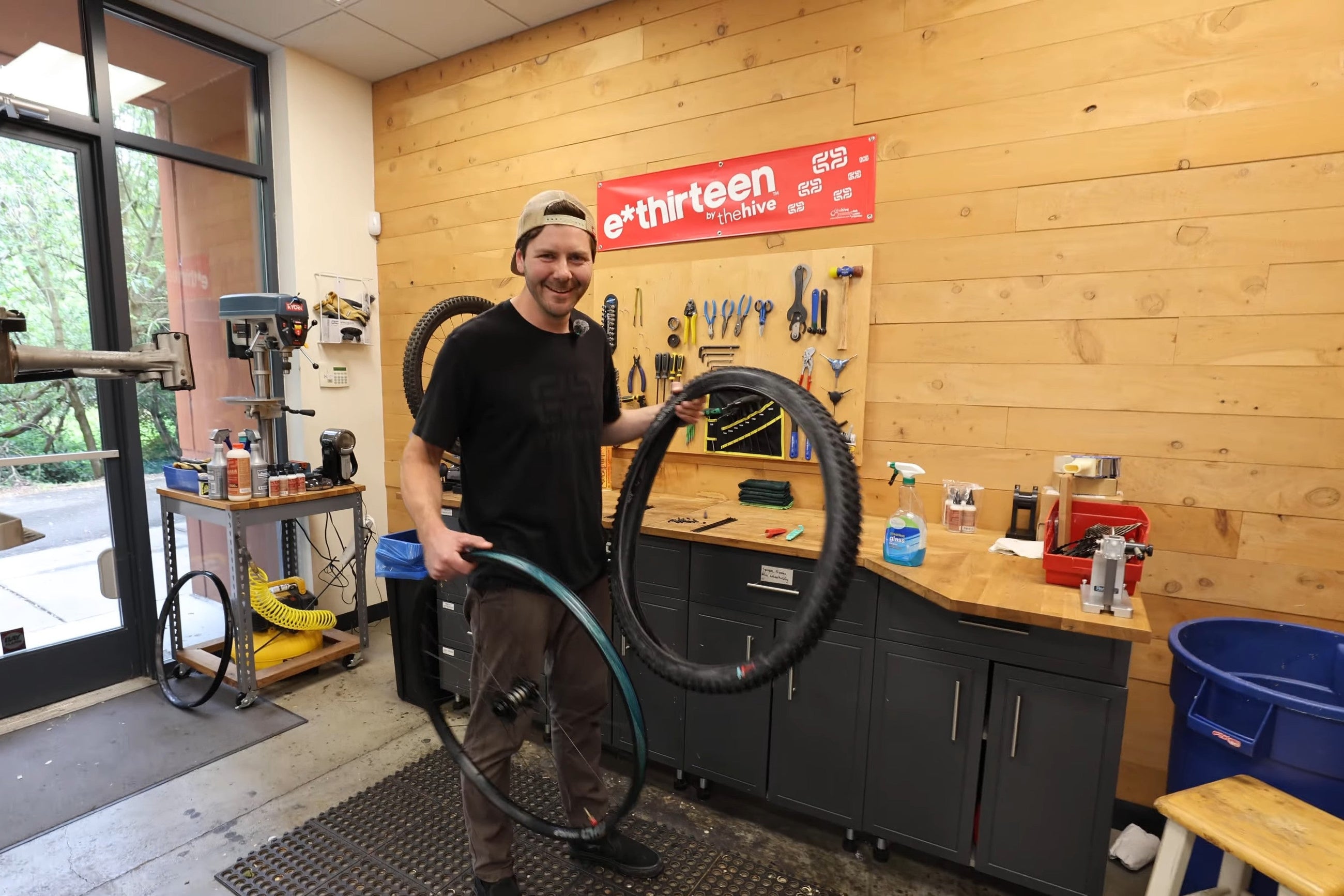 A mechanic in the e*thirteen workshop holding a Grappler Radial tire in one hand and a Flux rim in the other, ready to mount it.