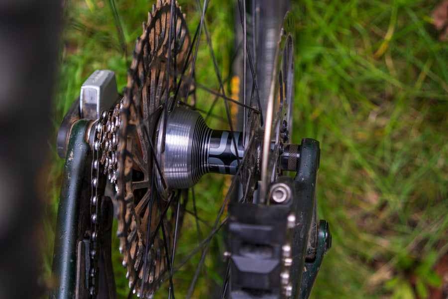 The first-generation Sidekick rear hub laced into a wheel on a bike, cassette alongside and grass behind.