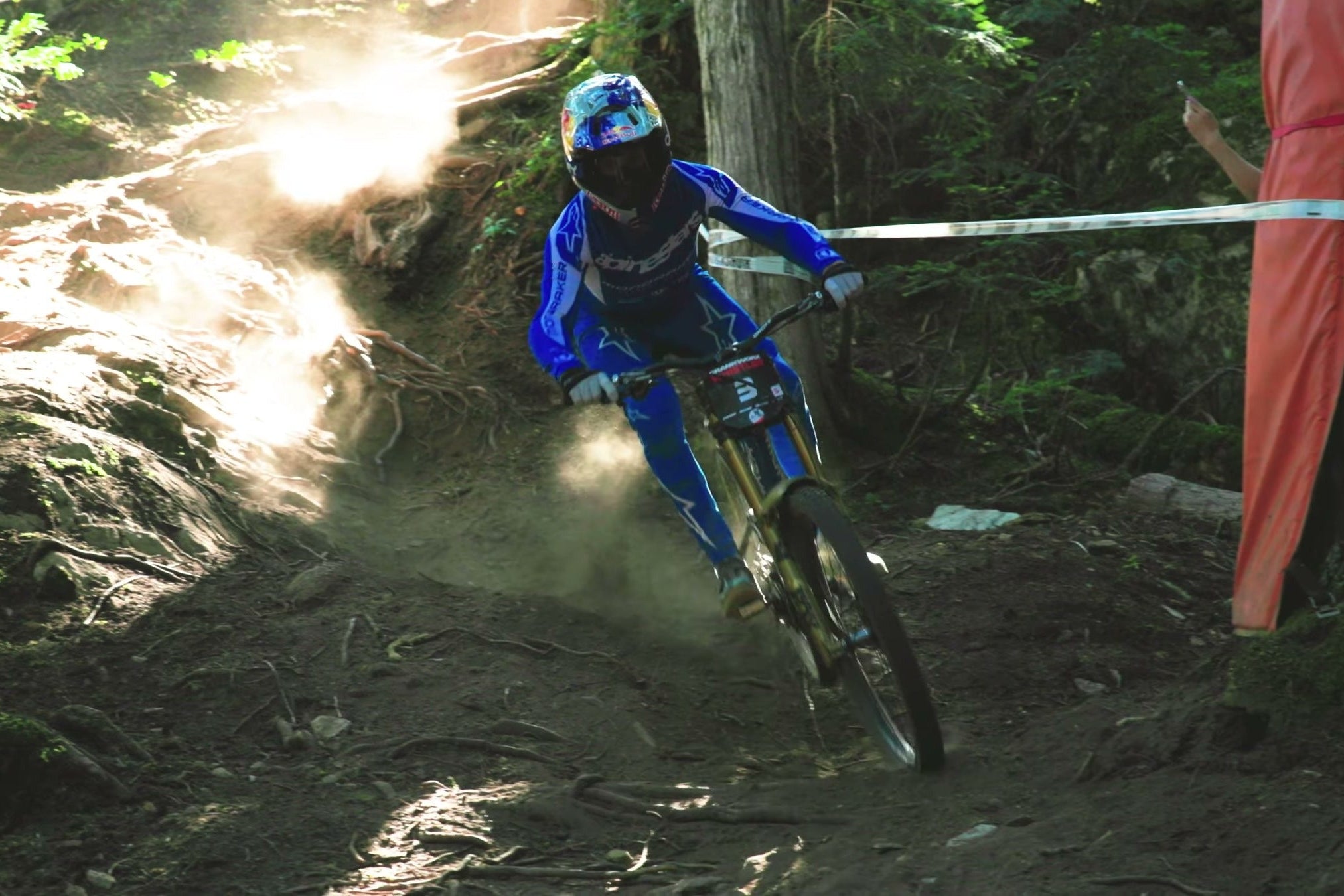 Ronan Dunne sliding a taped corner through a sunlit forest on his Mondraker, from our Sidekick pit video.