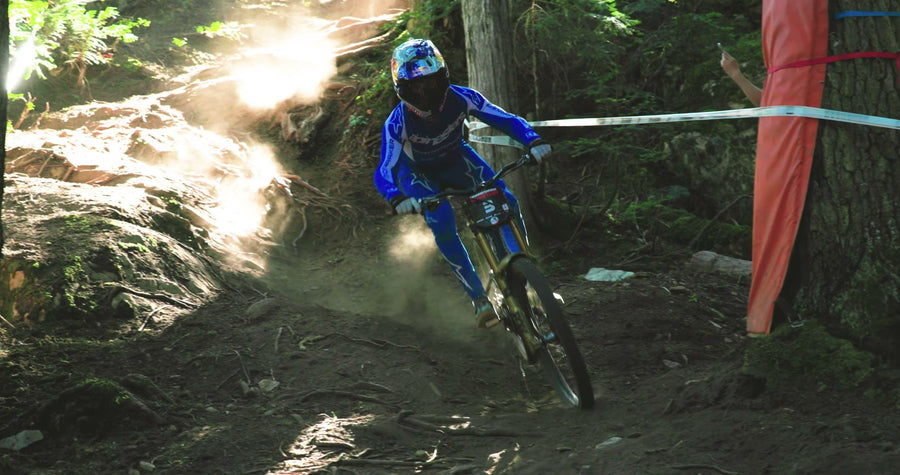 Ronan Dunne sliding a taped corner through a sunlit forest on his Mondraker, from our Sidekick pit video.