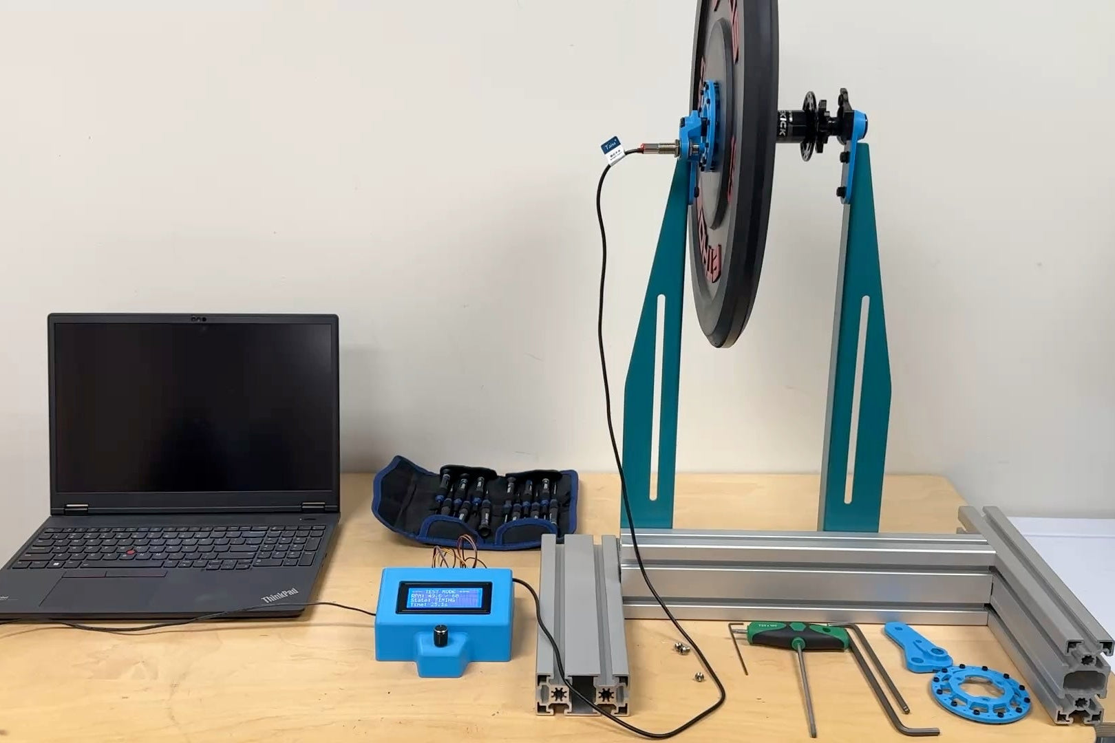 The spin-down test stand on the bench, the weighted plate and hub in the frame with the laptop and data logger alongside.
