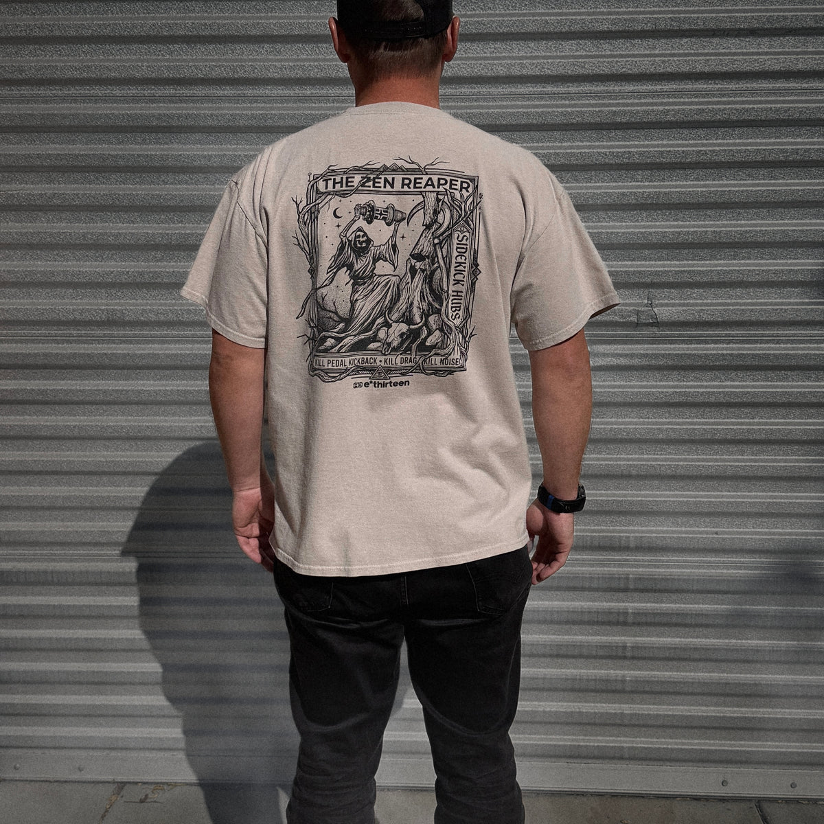 Back of the Zen Reaper T-shirt in Sand: a reaper holding a Sidekick hub, with the banner kill pedal kickback, kill drag, kill noise e*thirteen