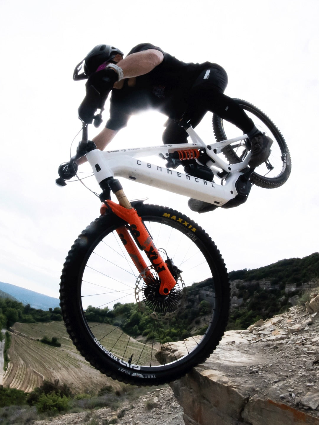 Alex Rudeau riding his Commencal Meta SX Power 800 off a rock ledge above a valley