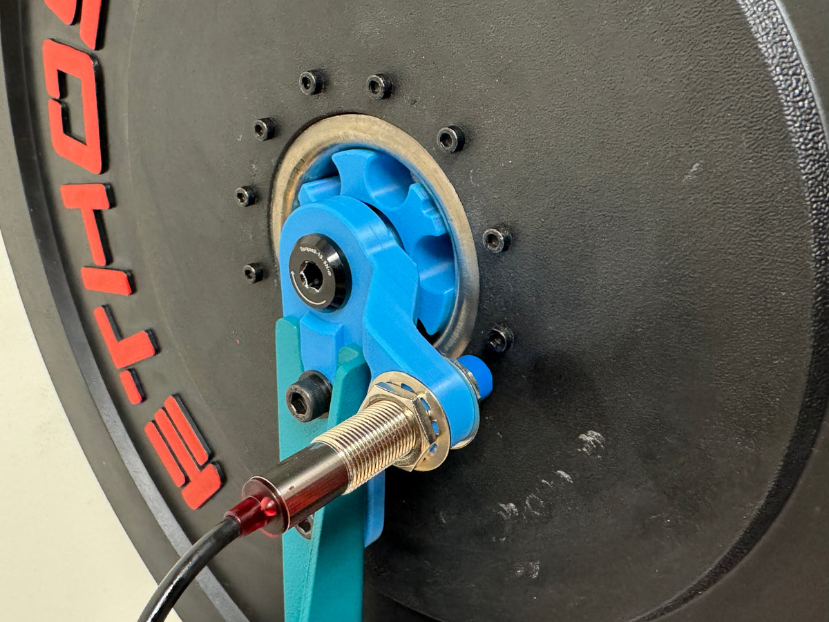 The inductive sensor aimed at the blue hub fixture on the weighted plate.