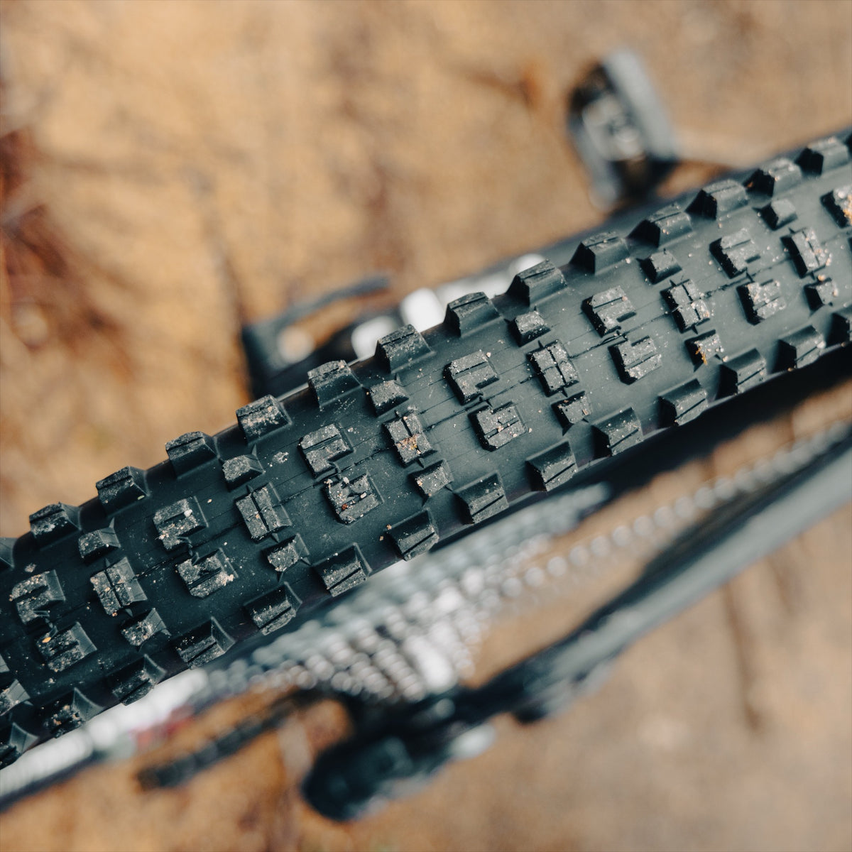 Close-up of a Grappler Radial tread packed with dried mud, the chain just behind it.
