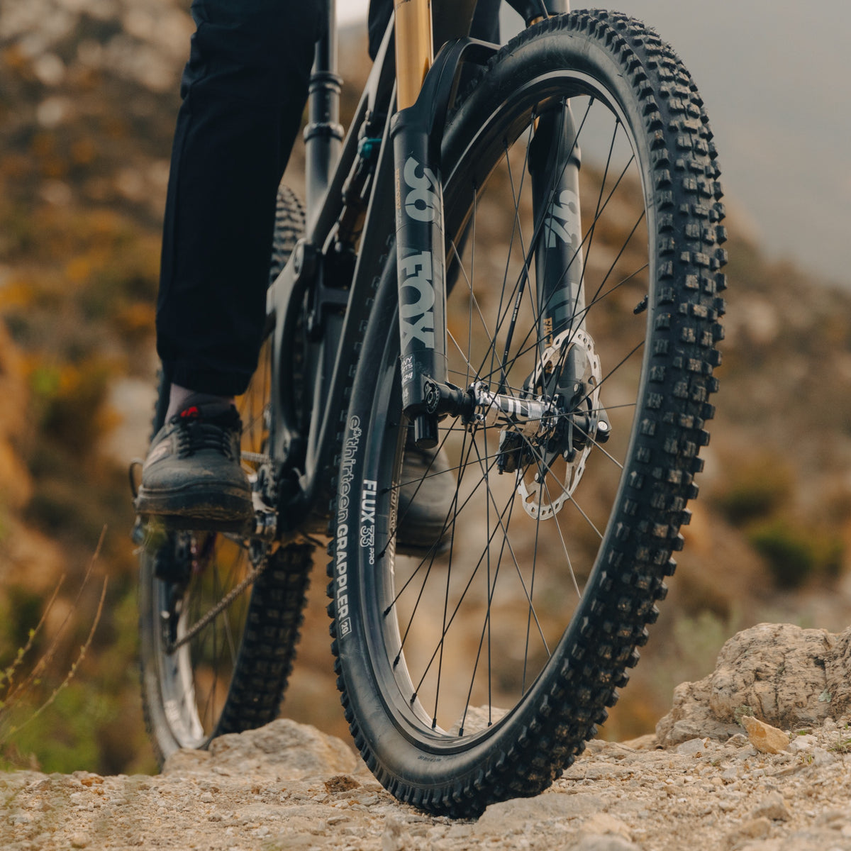 A Grappler Radial front tire on a Fox-forked bike, rolling across rock on a hazy ridge.