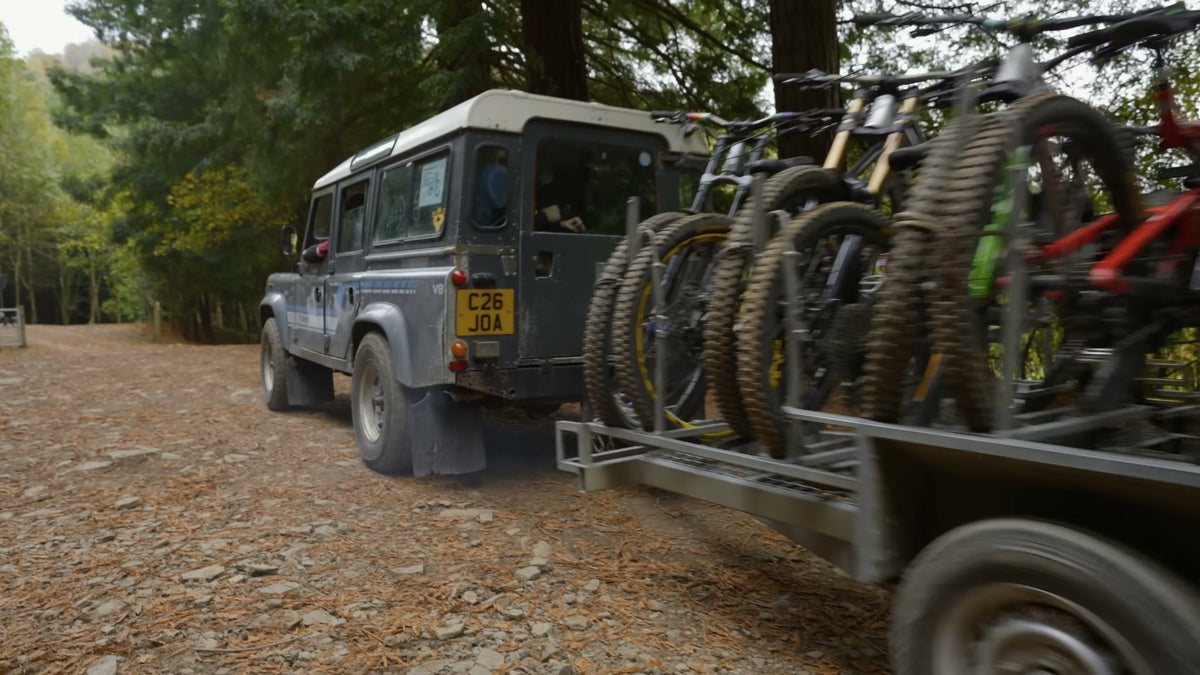 A Land Rover towing a trailer of demo bikes up the fire road at Redwood Park.