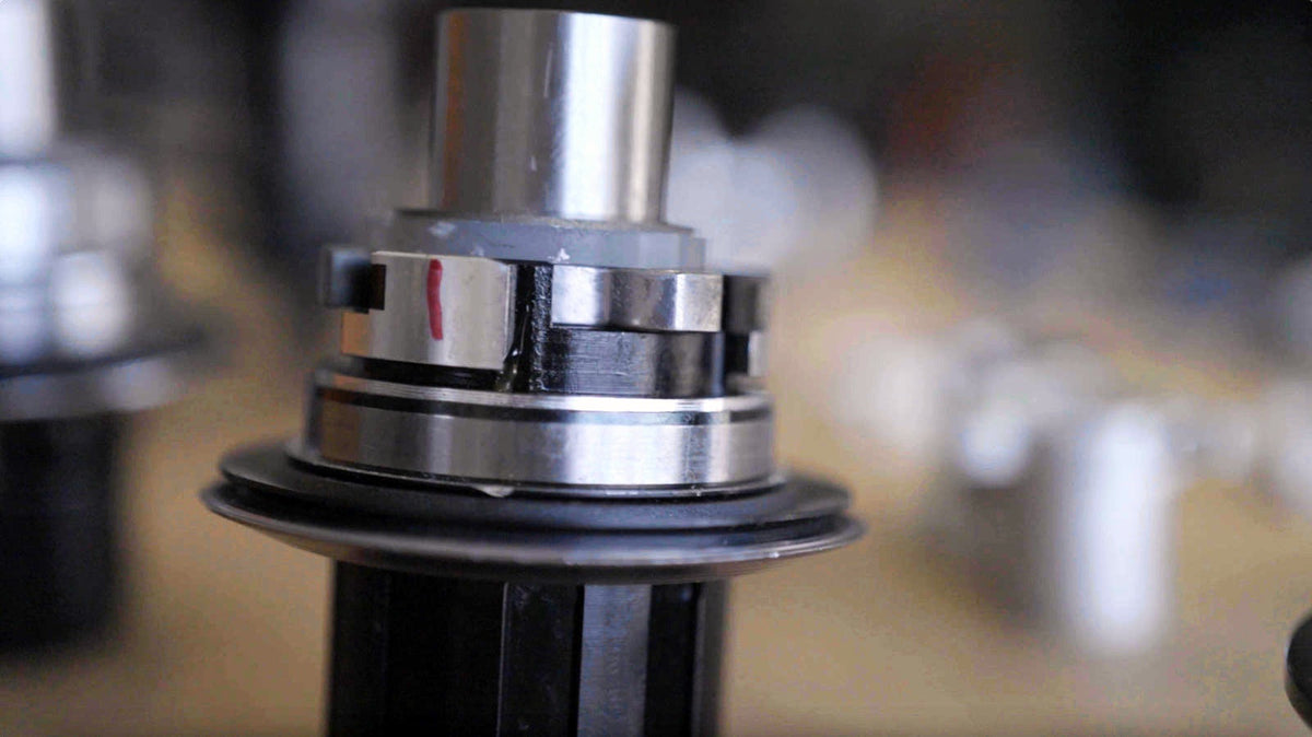 A Sidekick hub shell held in a machine, a red witness mark on the freehub